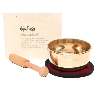 Brass singing bowl, a wooden striker and a simple cushion next to an elegant handmade Himalayan Lokta paper box