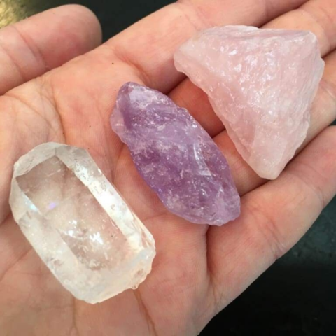 Close-up of healing crystals, featuring clear quartz, amethyst and rose quartz gemstones held in a hand for crystal healing and wellbeing.